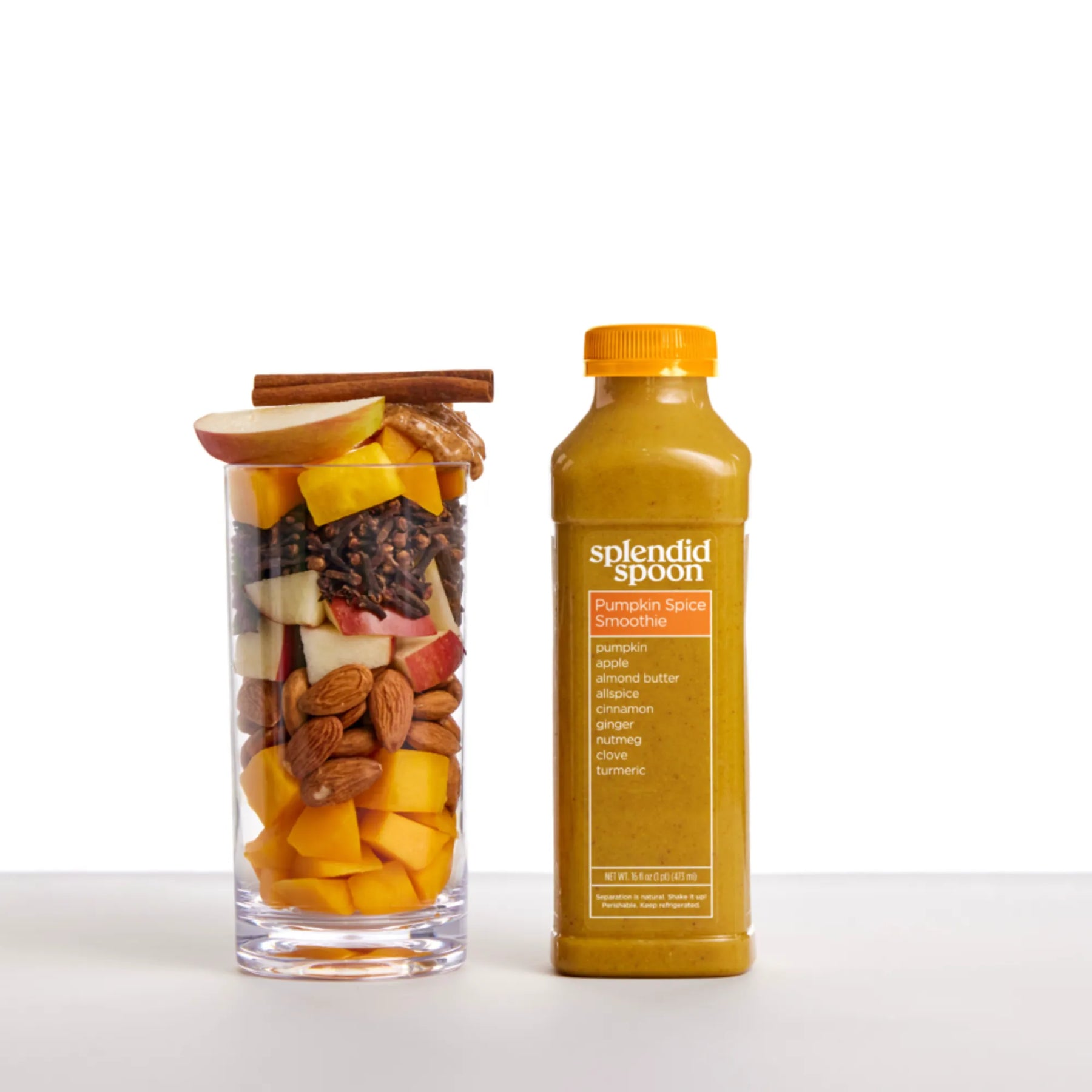 Bottle of Splendid Spoon pumpkin spice smoothie next to a glass filled with fruit and nuts on a white background