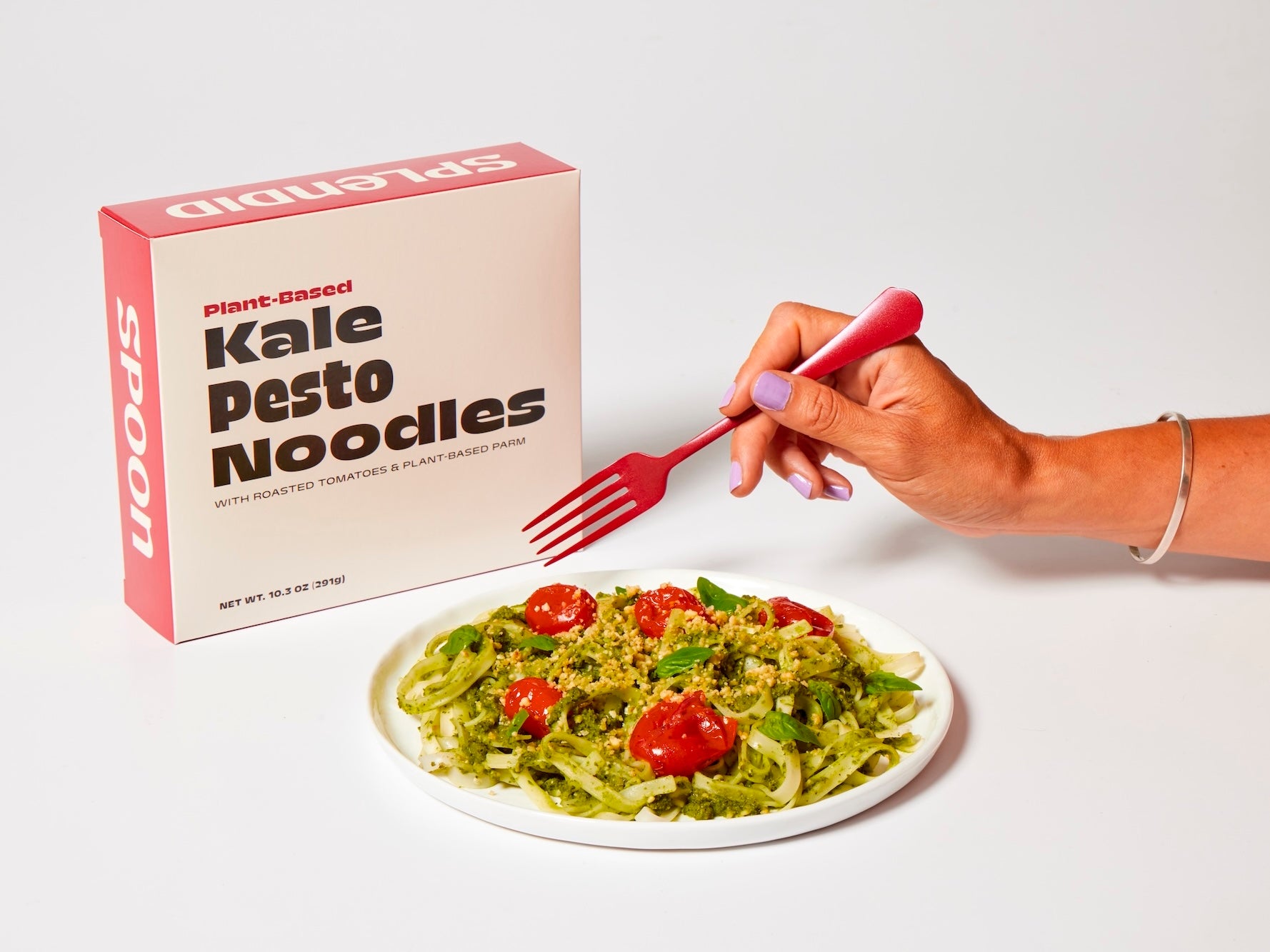 Splendid Spoon Kale Pesto Noodles with a hand holding a fork