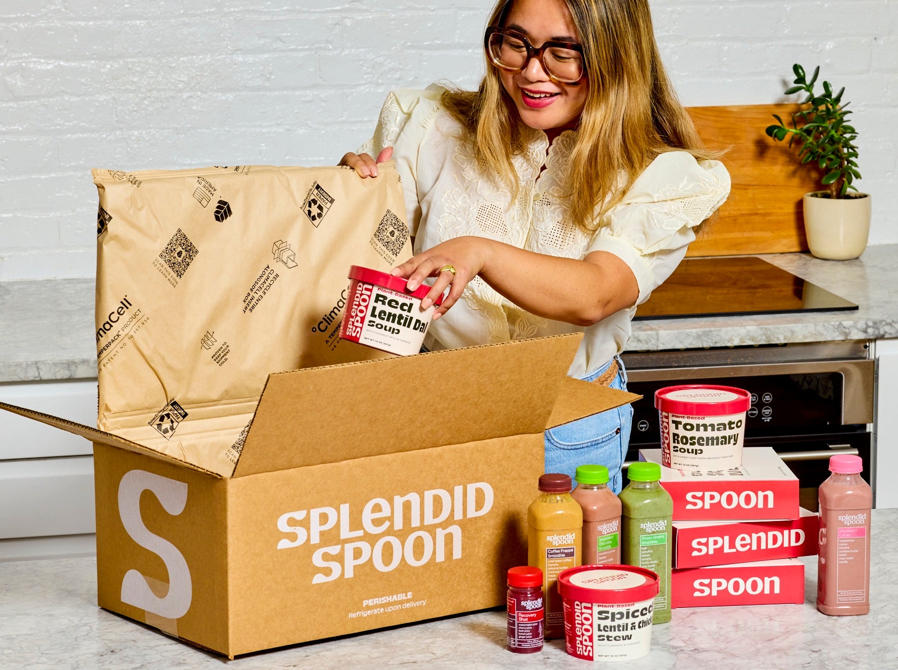 A smiling woman unboxing Splendid Spoon products