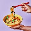 A hand pulling up noodles using chopsticks