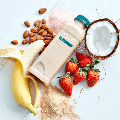 Abj smoothie in bottle with almonds, pink salt, strawberries, coconut, banana and baobab powder on a white background.
