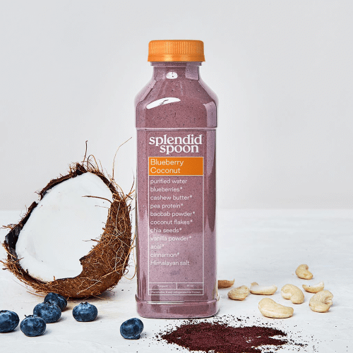 Cut coconut with blueberries, cashews, acai and Blueberry Coconut Smoothie bottle on white background. 