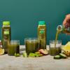 Green Juice Discovery Bundle in glasses, with one bottle being poured out into a cup on table.
