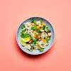 Green Curry Noodles in a dish on a peach background.