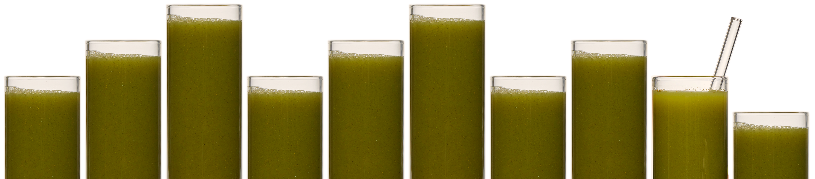 Many clear glasses of different heights filled with green juice. The second glass from the right has a glass drinking straw in it.