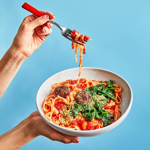 Vegan Meatballs & Marinara Noodles being held in the air with a fork of noodles