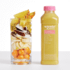 A clear glass filled with ingredients of the Pineapple Passion Fruit smoothie: pineapple, passion fruit, coconut, bananas, and sea buckthorn berry