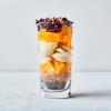 Clear glass with chia seeds, flax seeds, oranges, bananas and hibiscus with a white background.