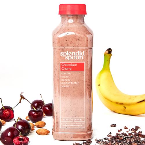 Chocolate cherry smoothie with cherries, almonds, cacao nibs, and banana on a white background.
