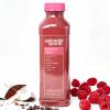Bottle of Raspberry Cacao with coconut, cacao nibs, & raspberries scattered around.