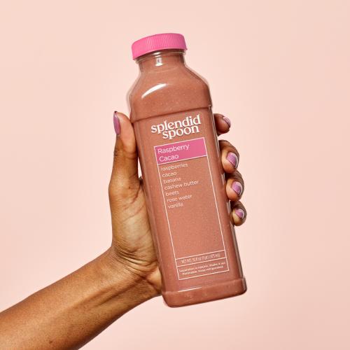 Hand holding Raspberry Cacao Bottle on a pink background