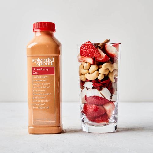 Strawberry Goji Smoothie next to a clear cup filled with its ingredients: strawberries, cinnamon, cashews, coconut