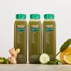 Three bottles of Super Greens Juice flanked by ingredients