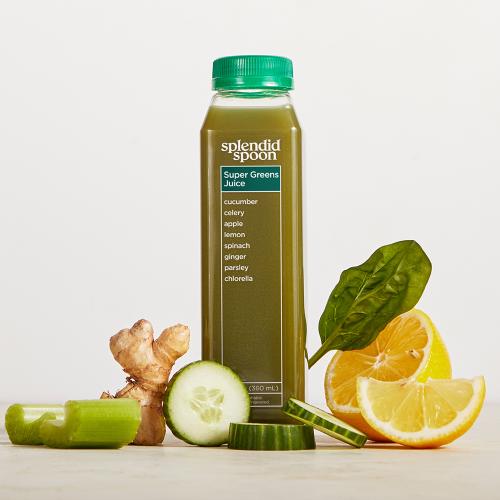 A single bottle of Super Greens Juice surrounded by ingredients